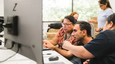 Employees viewing computer screen in modern office space at semiconductor manufacturing facility. 