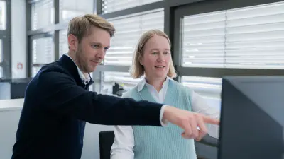 Anne Bedacht exchanging with a colleague in front of a screen