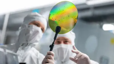 Two employees inspect a 200 mm silicon carbide (SiC) wafer